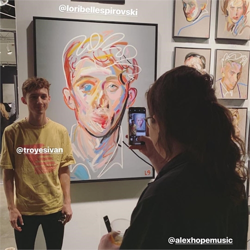 Troye Sivan posing with Loribelle Spirovski's portrait at the LA Art Show.